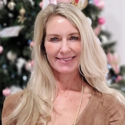 A woman standing in front of a christmas tree.